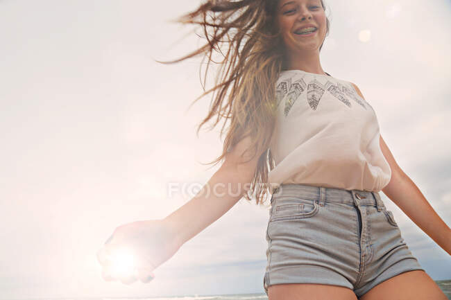 Porträt eines Teenie-Mädchens am Strand, lächelnd, Blick aus dem niedrigen Winkel — Stockfoto