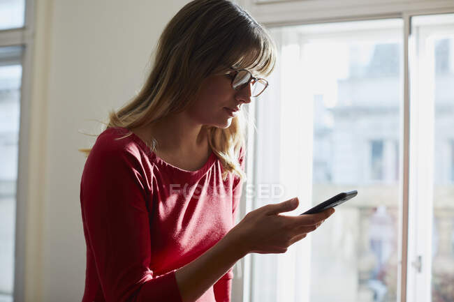 Geschäftsfrau schaut im Büro aufs Smartphone — Stockfoto
