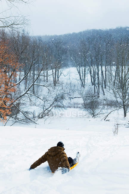 Rückansicht eines Mannes, der auf einem Hügel Schlitten fährt — Stockfoto