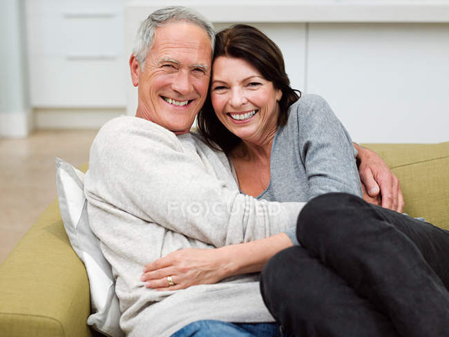 Ältere Paare umarmen sich auf Sofa im Wohnzimmer — Stockfoto