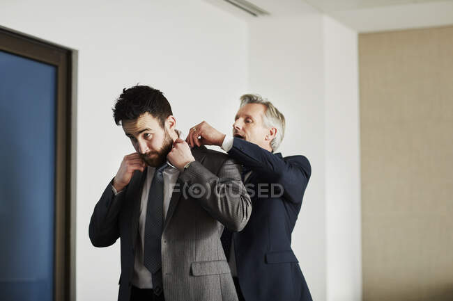 Senior businessman adjusting colleague's jacket in office — Stock Photo