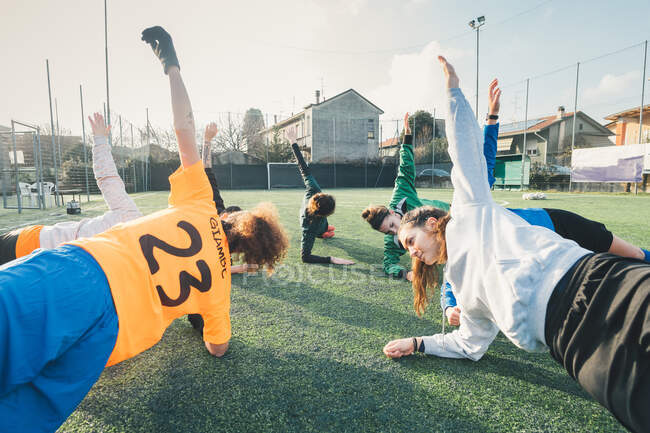 Jogadores de futebol em posição de prancha em campo — Fotografia de Stock