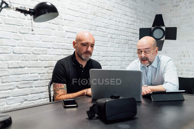 Коллеги в офисе смотрят вместе на ноутбук — стоковое фото