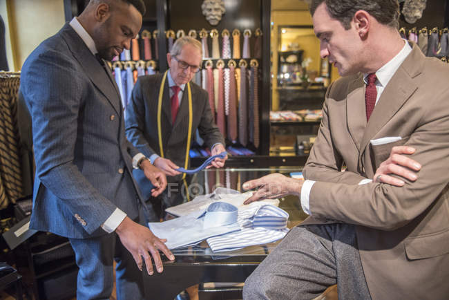 Tailor and customer looking at shirts in tailor shop — Stock Photo