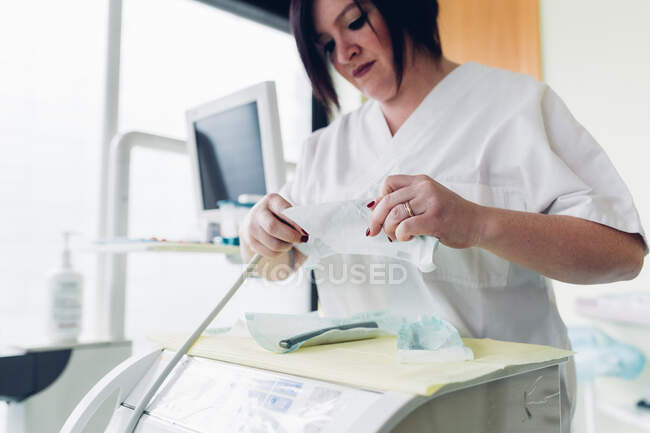 Dentista femenina en consultorio odontológico, preparando equipo odontológico - foto de stock