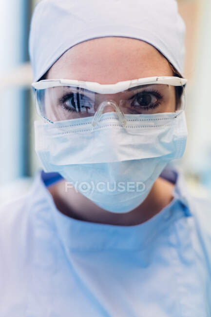 Retrato de dentista feminina, usando máscara cirúrgica e óculos de proteção, close-up — Fotografia de Stock