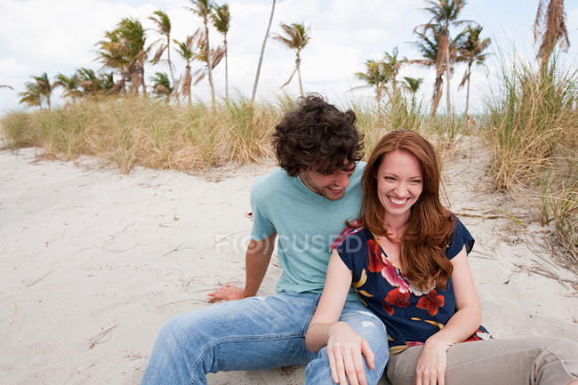 Retrato de pareja joven sentada en la playa - foto de stock