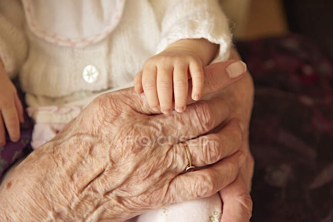 Seniorin hält Baby-Urenkelin in Nahaufnahme der Hände — Stockfoto