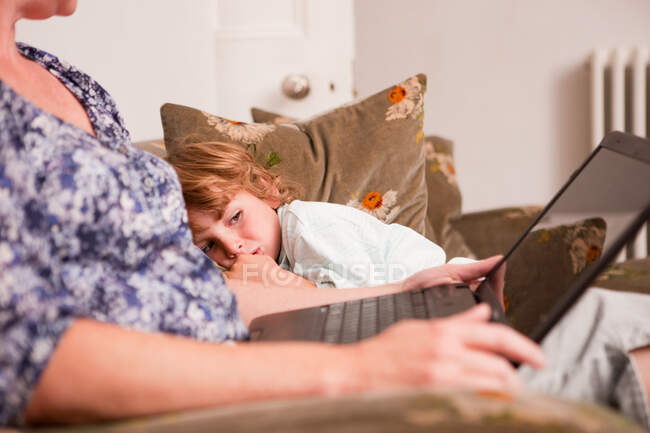 Menino assistindo mãe usar laptop — Fotografia de Stock