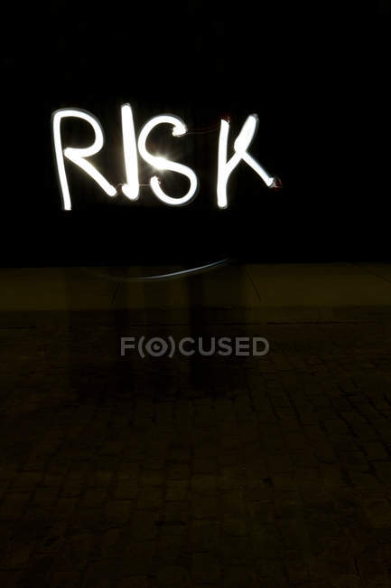 Inscription risk written with light on black background — Stock Photo