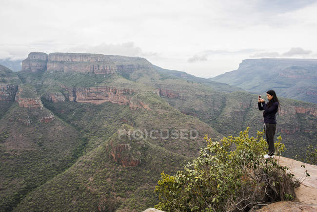 Далекий взгляд молодой женщины туристической фотографируя пейзаж из трех Rondavels, Мпумаланга, Южная Африка — стоковое фото