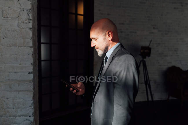 Портрет бизнесмена, смотрящего вниз на смартфон — стоковое фото