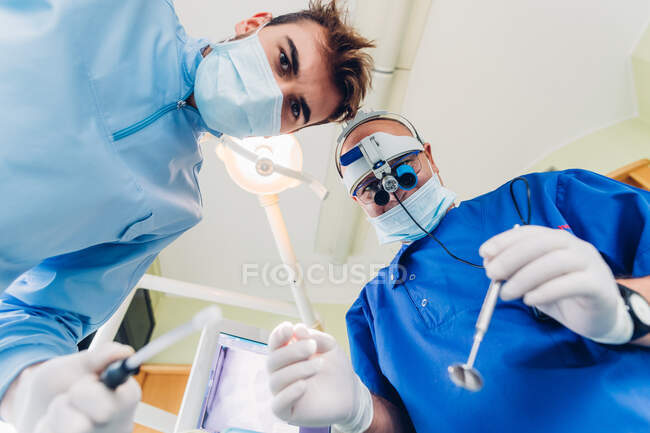 Dentista e enfermeira dentária tratando paciente, perspectiva pessoal — Fotografia de Stock