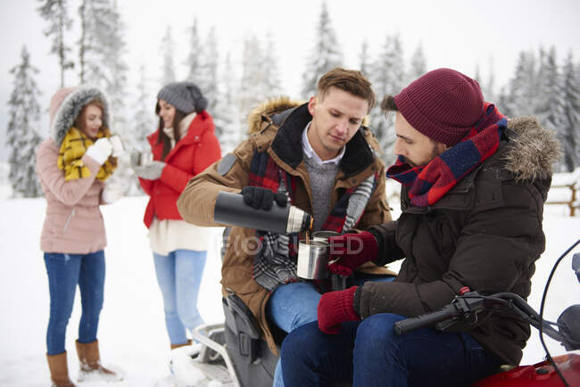 Друзья зимой пьют кофе на открытом воздухе — стоковое фото