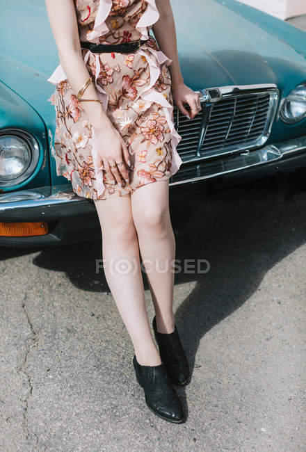 Vista recortada de la mujer apoyada contra el coche vintage - foto de stock