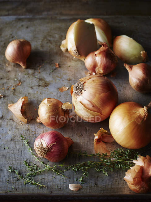 Vue rapprochée des oignons, échalotes et thym sur la vieille table rustique — Photo de stock