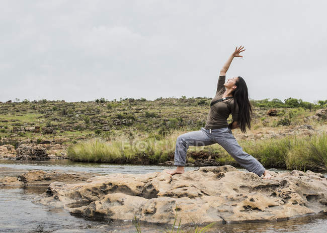 Vista a distanza di Giovane turista femminile praticare posa guerriero yoga a Bourkes Potholes, Mpumalanga, Sud Africa — Foto stock