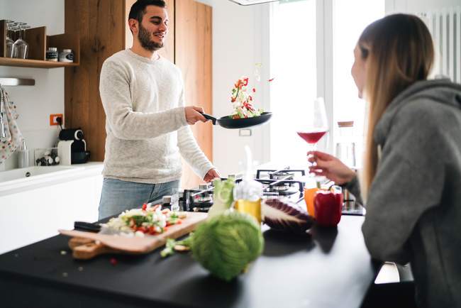 Пара готує їжу, кидає овочі на сковороду — стокове фото