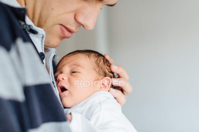 Father holding newborn baby girl to his chest, mid section, close-up — Stock Photo