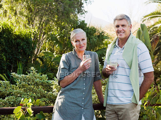 Зрелая пара пьет вино в саду — стоковое фото