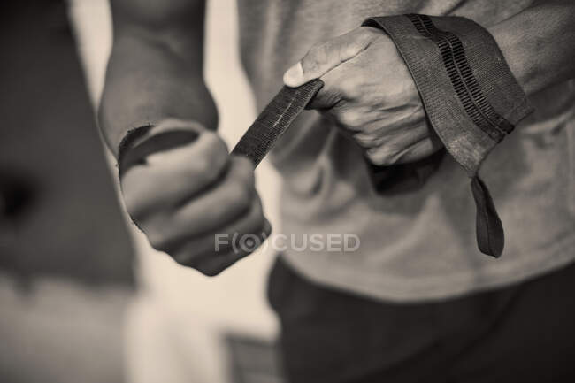 Vista ritagliata di mani uomo reggiatura con cinghie di sollevamento pesi — Foto stock