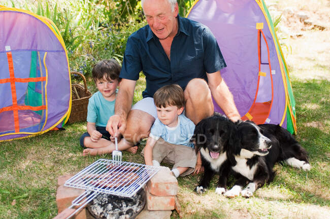Grand-père et petits-fils faisant un barbecue — Photo de stock
