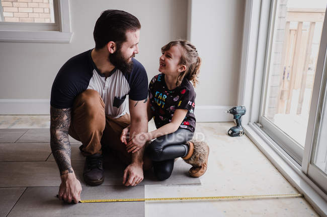 Menina ajudando o pai a instalar telhas do chão — Fotografia de Stock