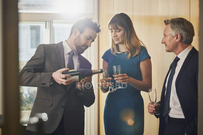 Бизнесмен разливает шампанское на офисном празднике — стоковое фото