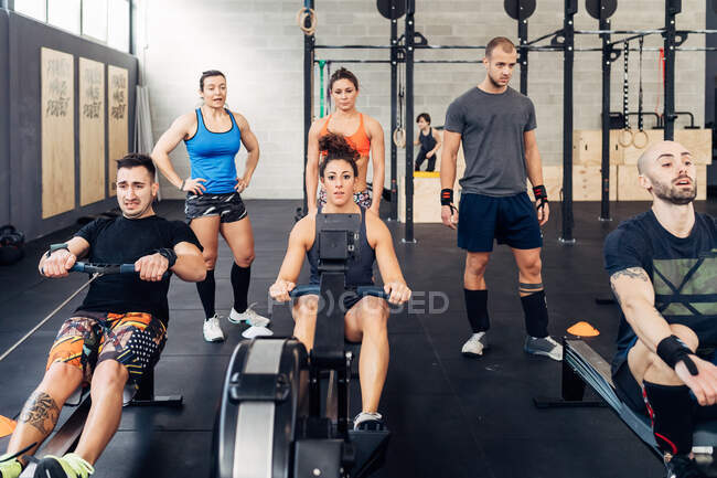 Menschen mit Rudergeräten im Fitnessstudio — Stockfoto