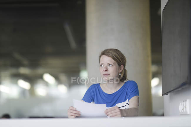Woman working in office and holding document — Stock Photo