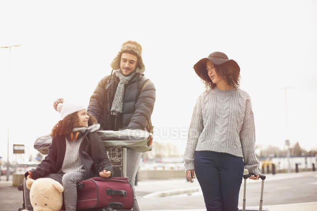 Girl with parents riding on luggage trolley — Stock Photo