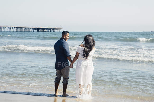 Casal em pé na praia, de mãos dadas, vista traseira, Seal Beach, Califórnia, EUA — Fotografia de Stock
