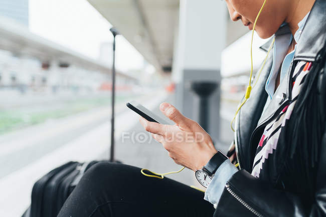 Woman on train platform using smartphone — Stock Photo