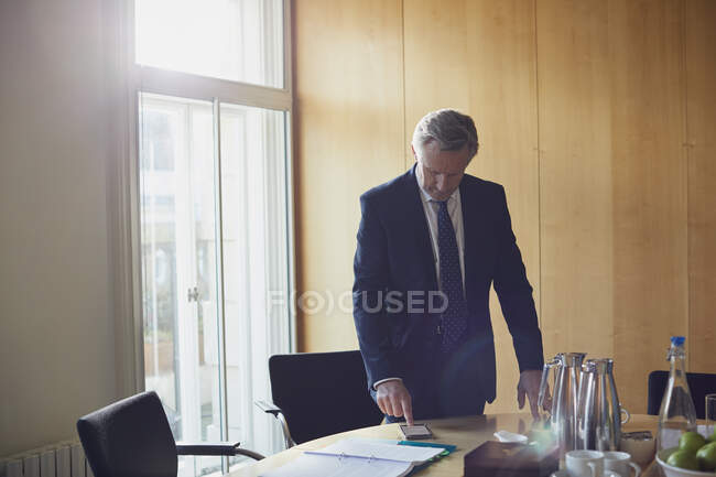 Businessman looking at smartphone on boardroom table — Stock Photo