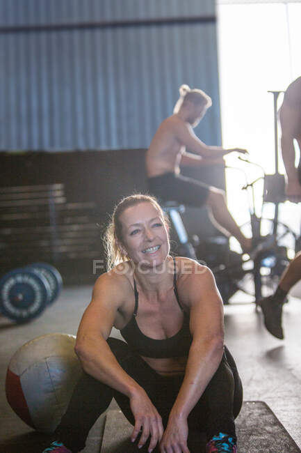 Gruppo di persone che fanno ginnastica in palestra, donna seduta in primo piano — Foto stock