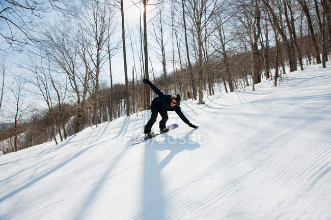 Homem snowboard na neve caped floresta — Fotografia de Stock