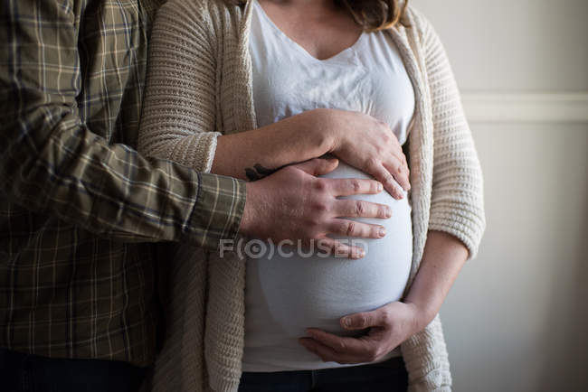 Mulher grávida tocando no estômago, parceiro mostrando afeto, seção meados — Fotografia de Stock