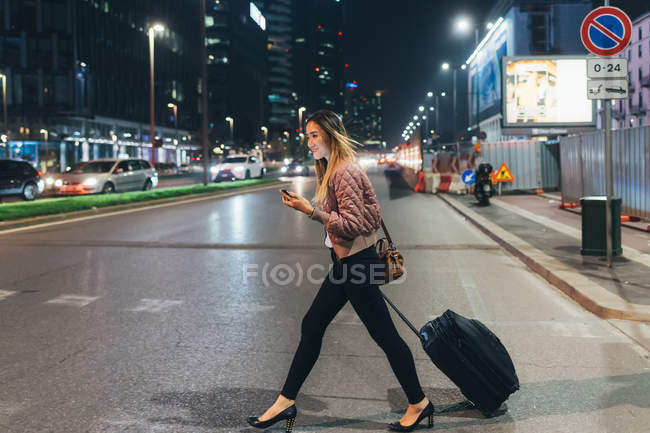 Donna che cammina all'aperto con valigia a ruote — Foto stock