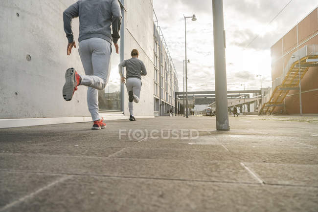 Visão traseira de jovem do sexo masculino correndo ao longo da calçada da cidade — Fotografia de Stock