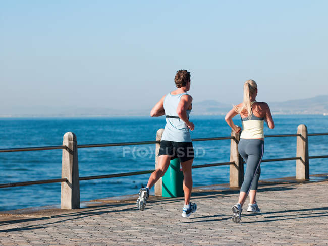 Jovem casal correndo por mar — Fotografia de Stock