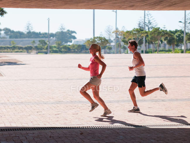 Young couple running in sportswear outdoors at daytime — Stock Photo