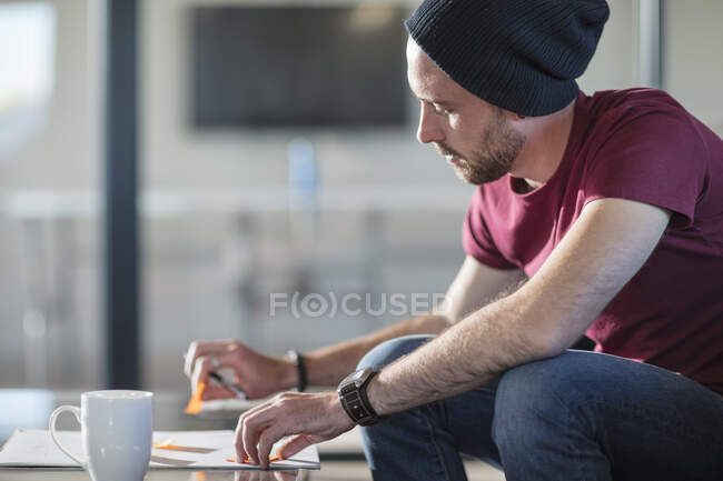 Молодой человек делает заметки во время перерыва на кофе в офисе — стоковое фото
