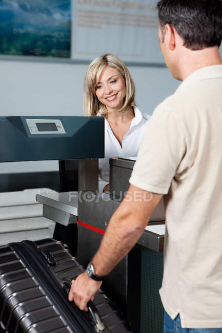 Man with luggage at check in desk of airport — Stock Photo