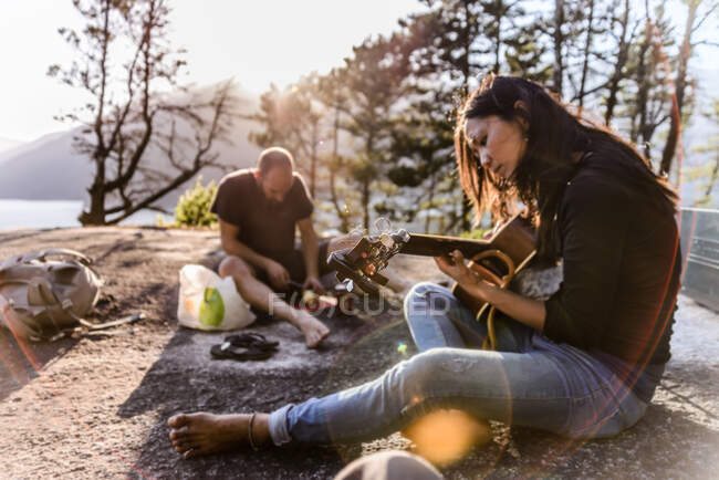 Homme et femme relaxants, cuisinant et jouant de la guitare sur The Malamute, Squamish, Canada — Photo de stock