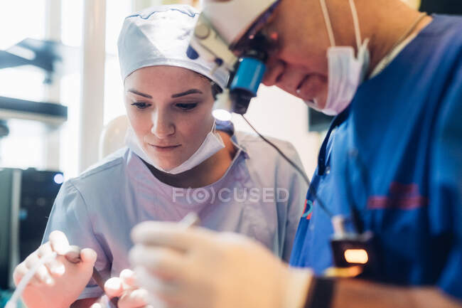 Dentista y enfermera dental usando equipo dental - foto de stock