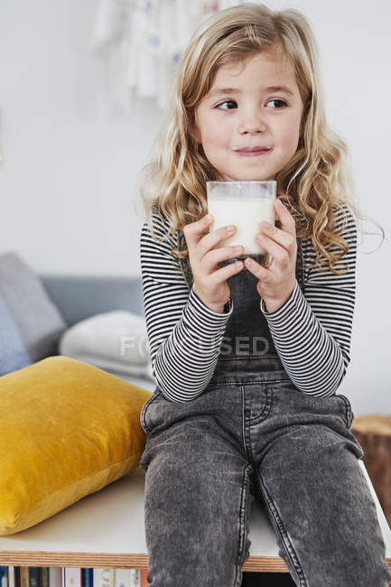 Menina na sala de estar segurando copo de leite — Fotografia de Stock