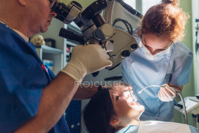 Dentist and dental nurse carrying out dental procedure on female patient — Stock Photo