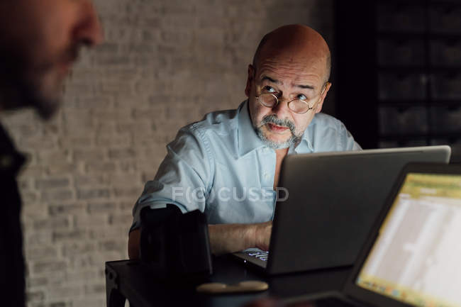 Male colleagues using laptops in office — Stock Photo