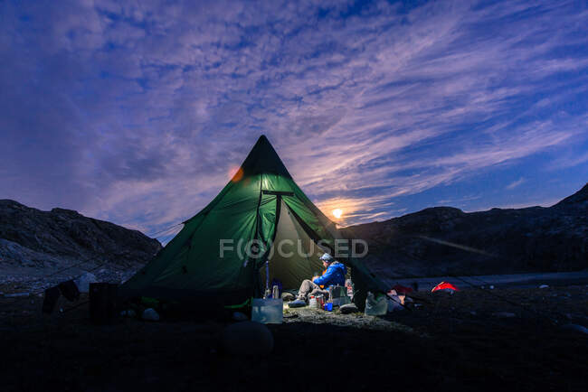 Uomo seduto in tenda illuminata al tramonto, Narsaq, Vestgronland, Groenlandia meridionale — Foto stock