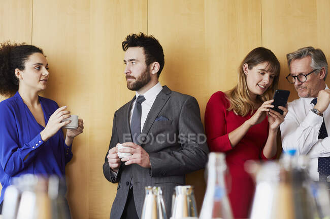 Бізнес-леді та чоловіки спілкуються перед офісною зустріччю — стокове фото